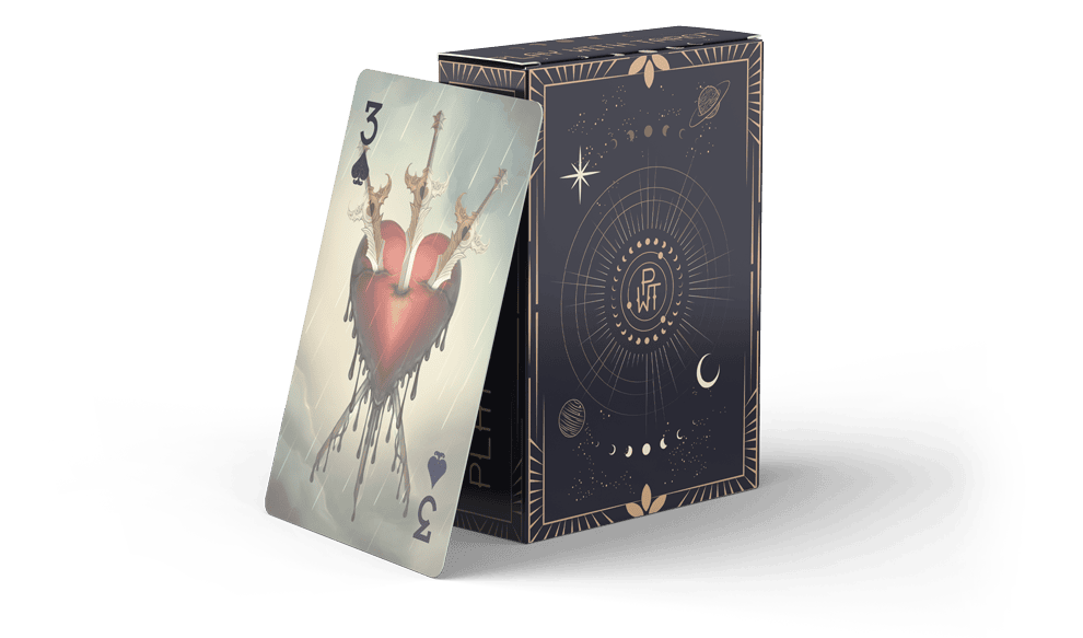 A playing card showing the 3 of hearts with a surreal, melting heart design leans against an ornate, dark-colored deck box featuring celestial symbols like stars, planets, and moons.